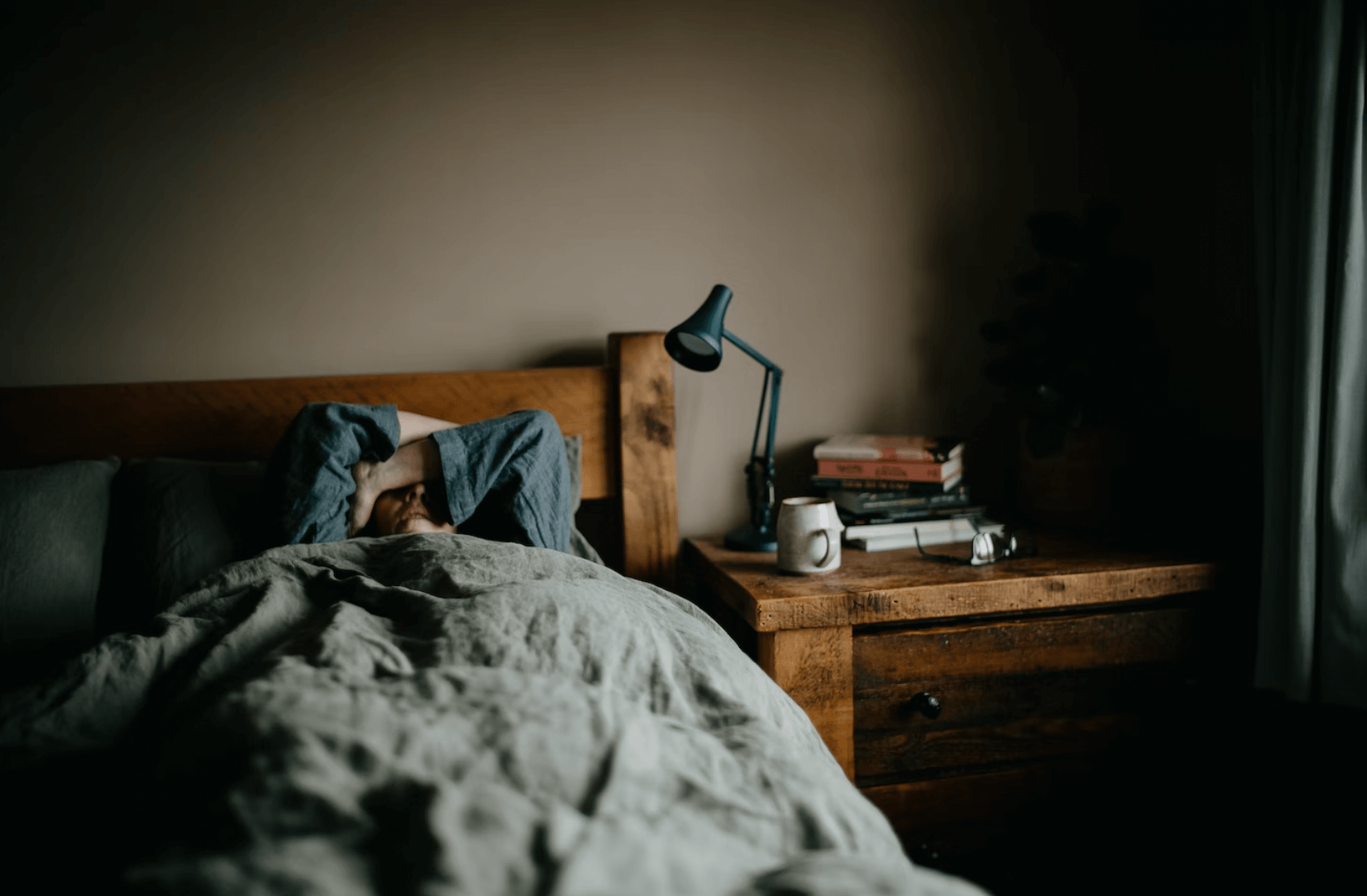 Jeugdzorg en frustraties: mens in bed met nachtkastje met lamp