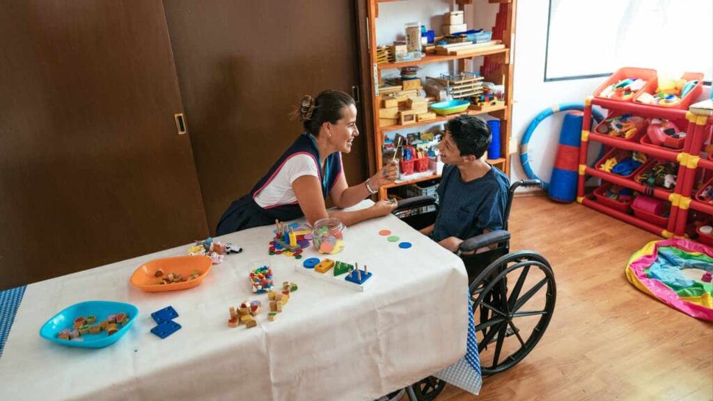 begeleider met gehandicapte aan tafel met spelletjes