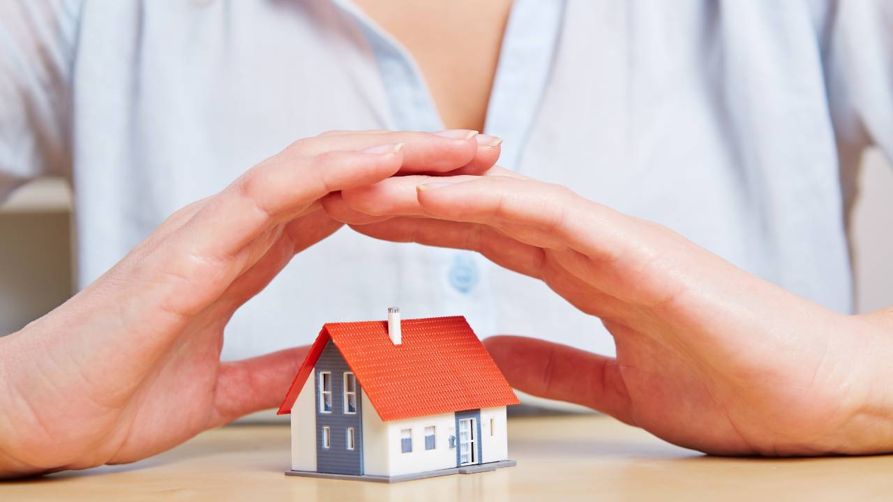 handen gevouwen boven een mini huis veiligheid open jeugdzorg groep