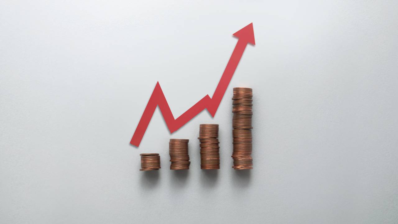 stapels met koperen munten en rode diagonale pijl die groei aangeeft